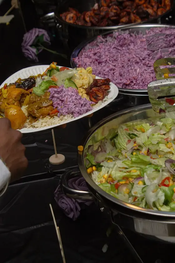 A wedding buffet with jollof rice, purple cabbage salad and chafing dishes