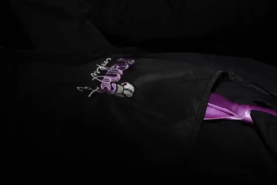 Close-up of the embroidered Rena Cooked It logo on a black uniform