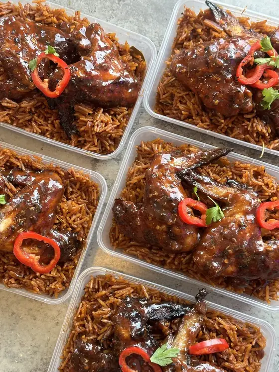 Meal prep containers of jollof rice and chicken with red peppers