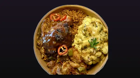 A takeaway bowl of jollof, chicken and mac and cheese on a dark background